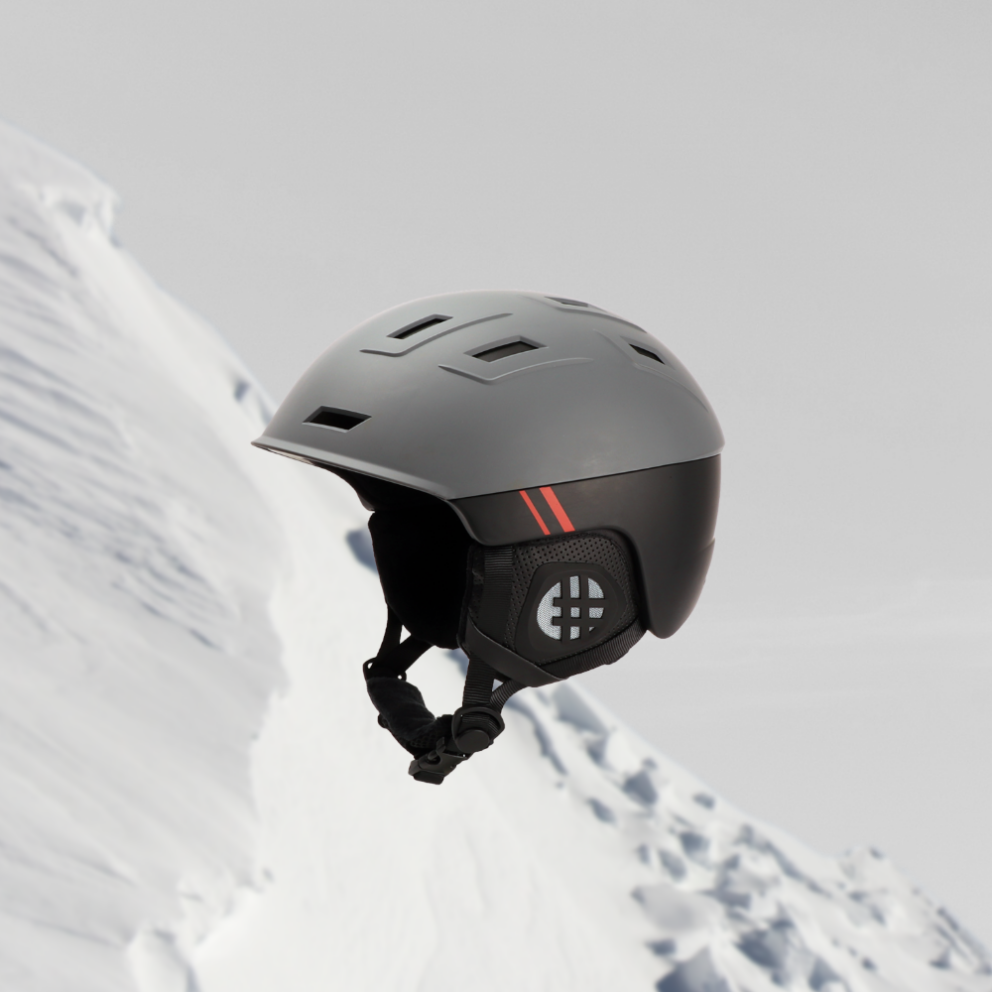 casque snowboard gris et noir suspendu sur fond de pente enneigée