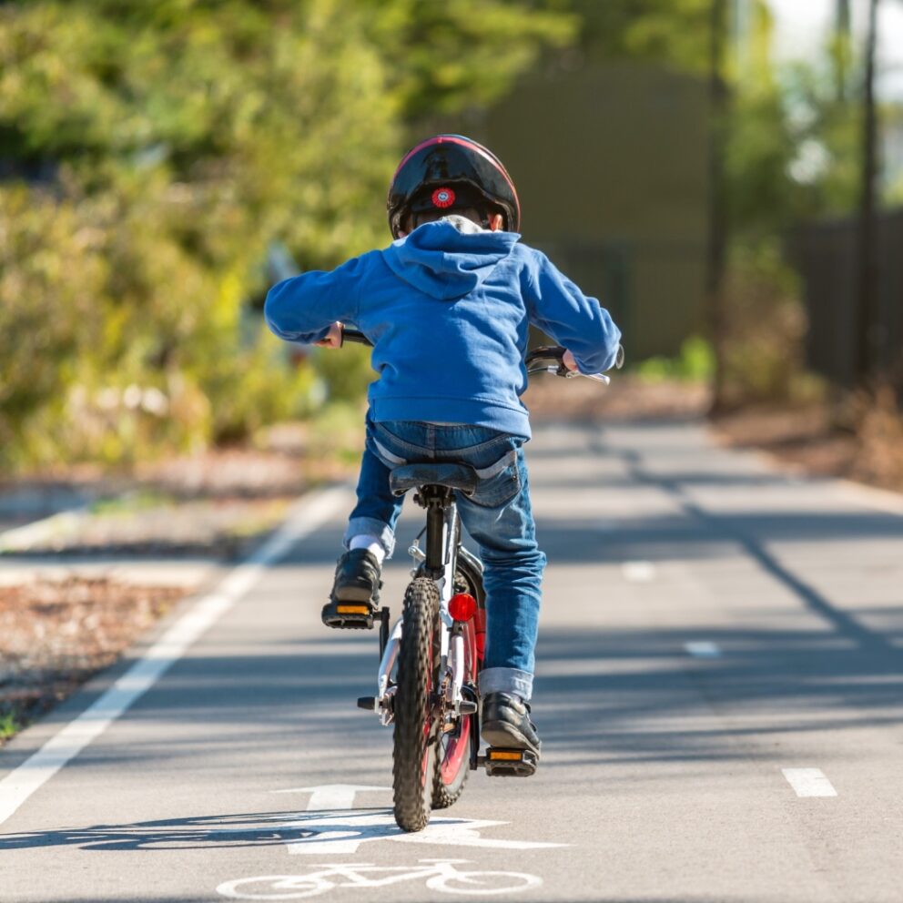 Enfant roulant à vélo sur une piste cyclable, casque bien positionné, environnement sécurisé